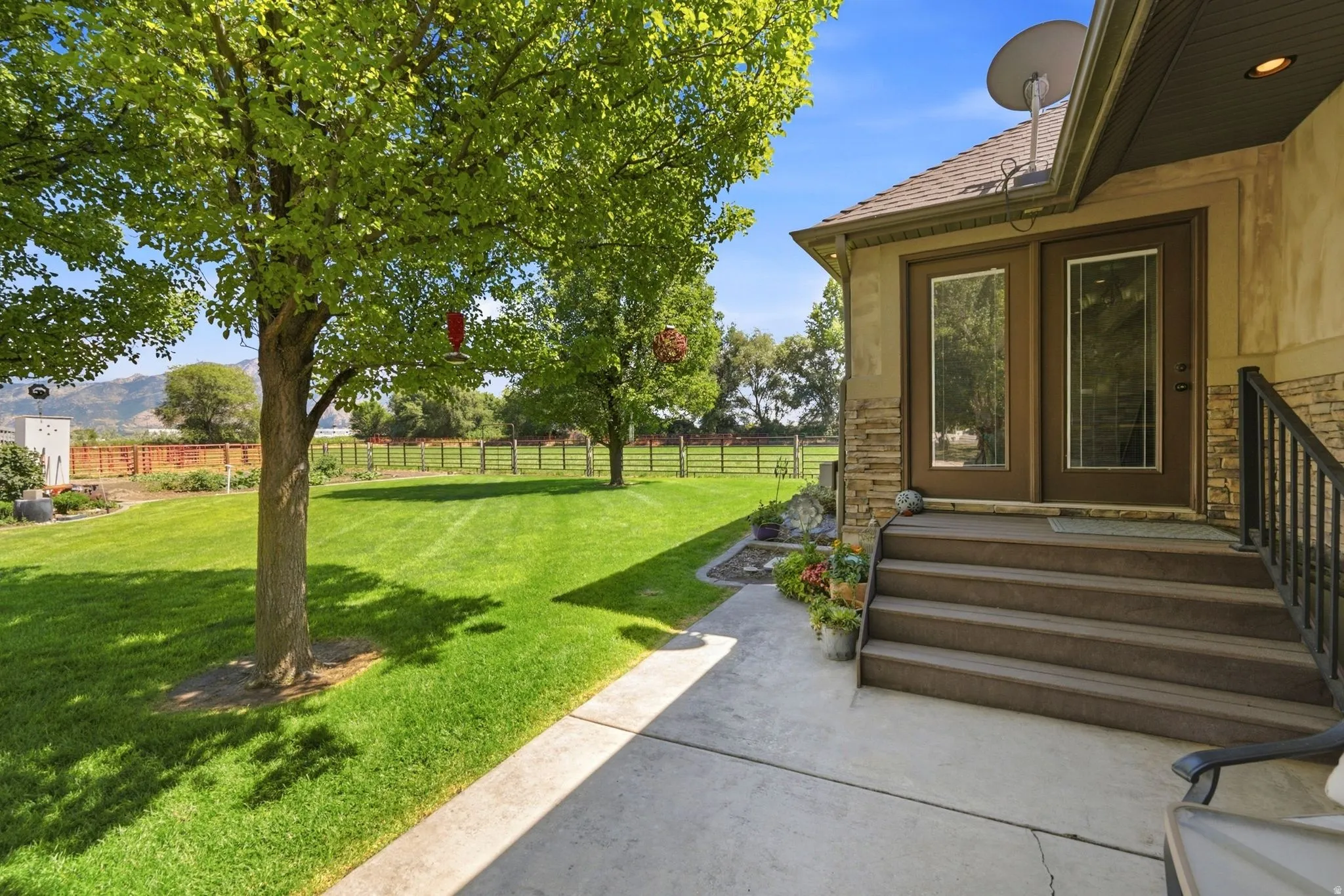 Expansive green lawn with mature trees and a fenced perimeter