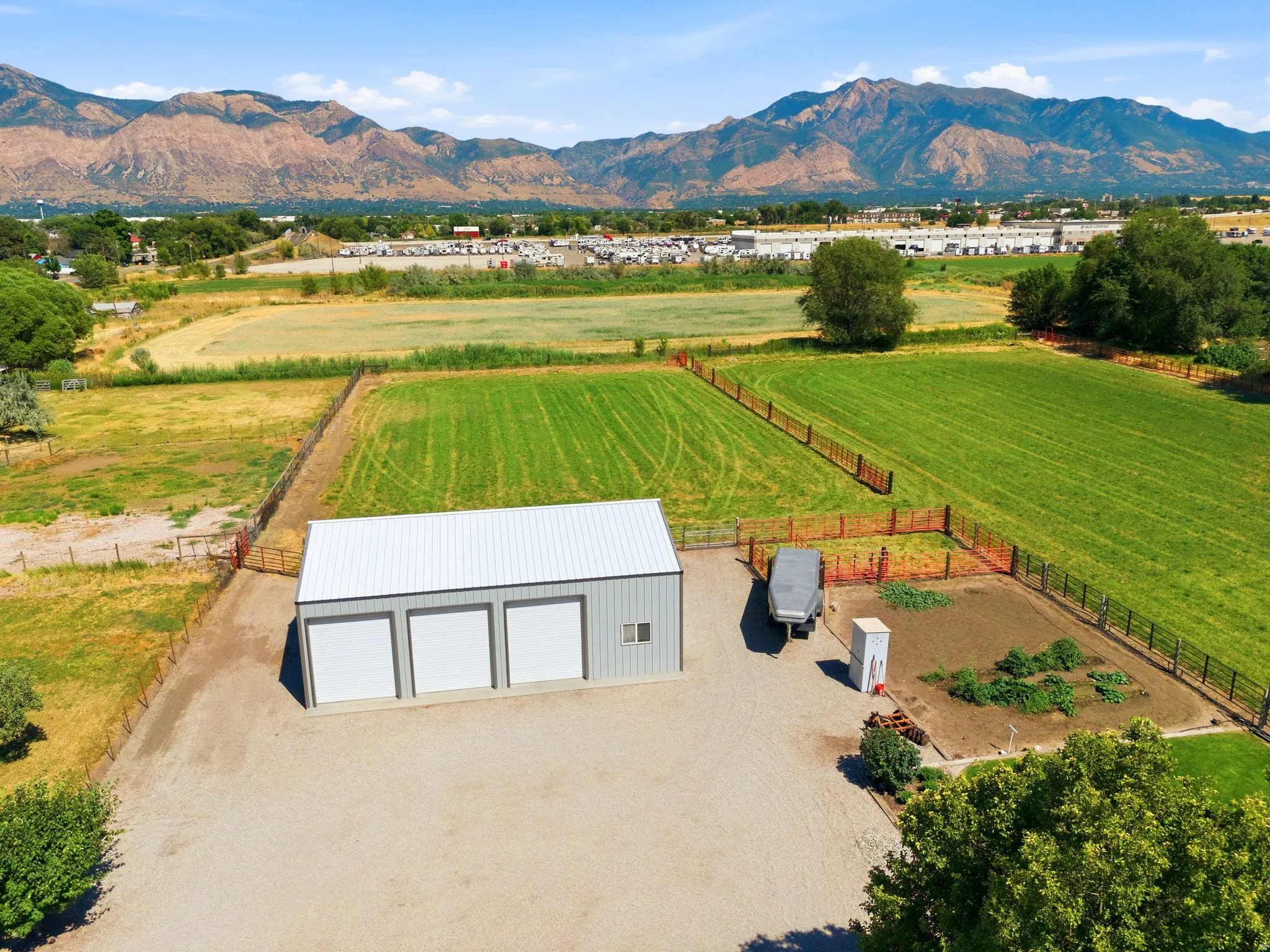 Multi-bay outbuilding with a metal roof and three overhead doors, situated on a large gravel pad