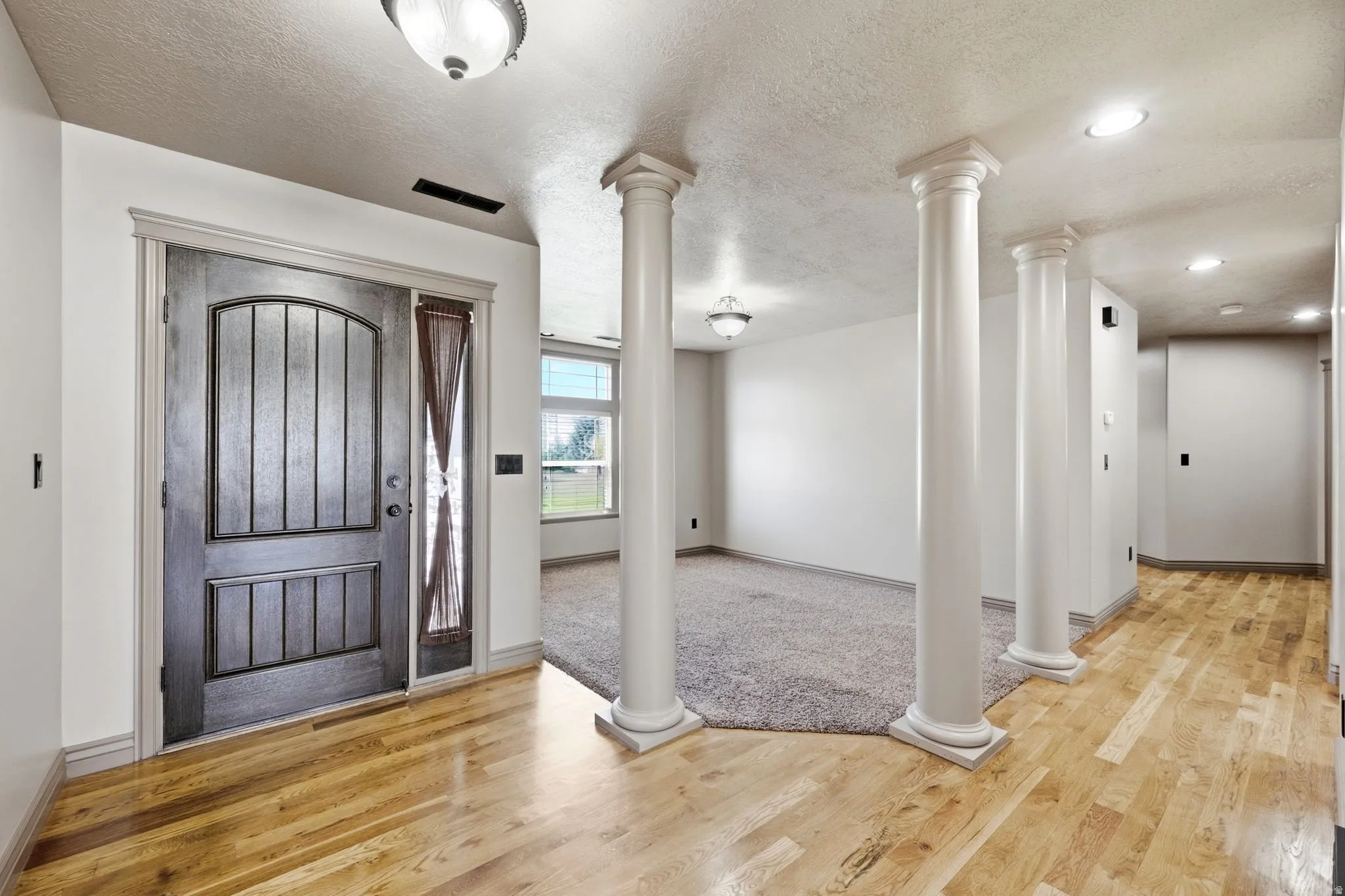 Hardwood flooring in the entryway with a paneled front door and sidelight