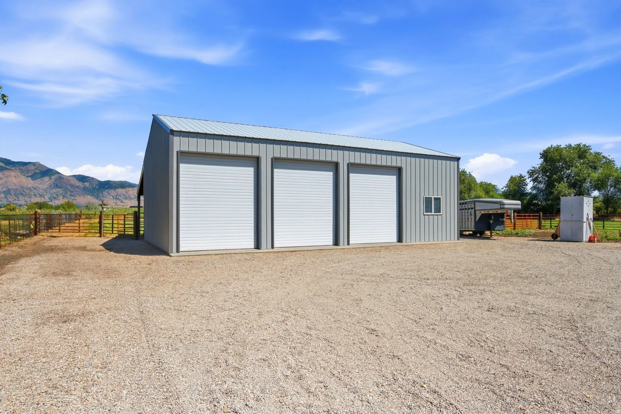Three-bay metal outbuilding with a gravel driveway