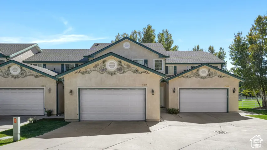 Stucco exterior featuring decorative gable accents, attached single-car garage, and a concrete driveway
