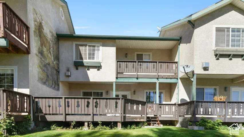 Exterior stucco finish, multiple private balconies, ground-level deck, decorative railing features, and a wall mural