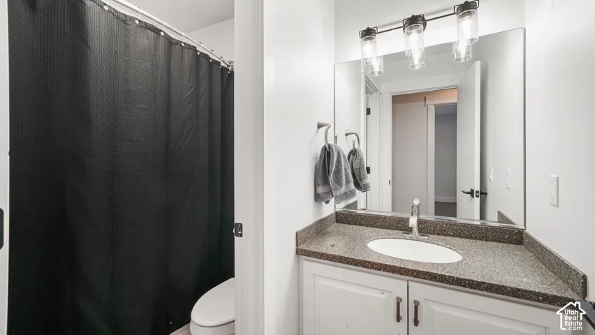 Shower tub, vanity with a speckled countertop, undermount sink, and brushed nickel faucet