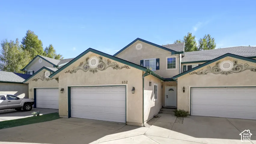 Stucco exterior with decorative gables, attached garage, and a covered entry