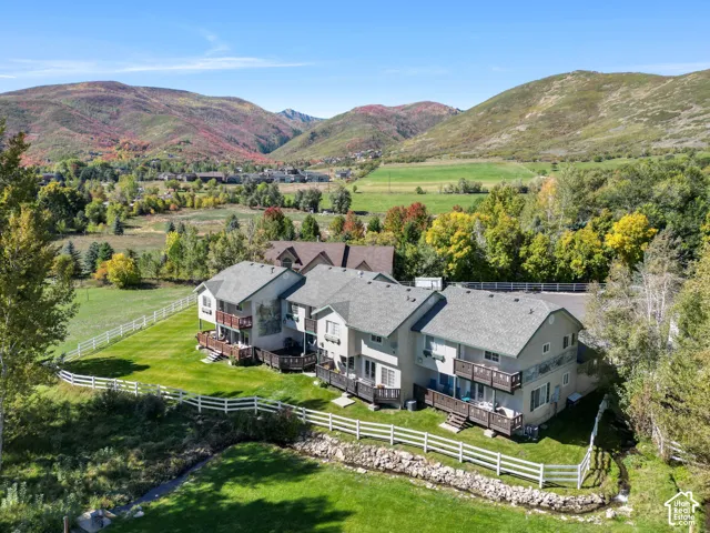 Terraced townhomes with private decks, individual balconies, and a white picket fence bordering a natural creek