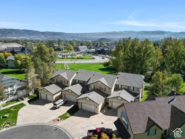 Aerial perspective showcasing multiple units with attached garages, paved driveways, and surrounding green spaces