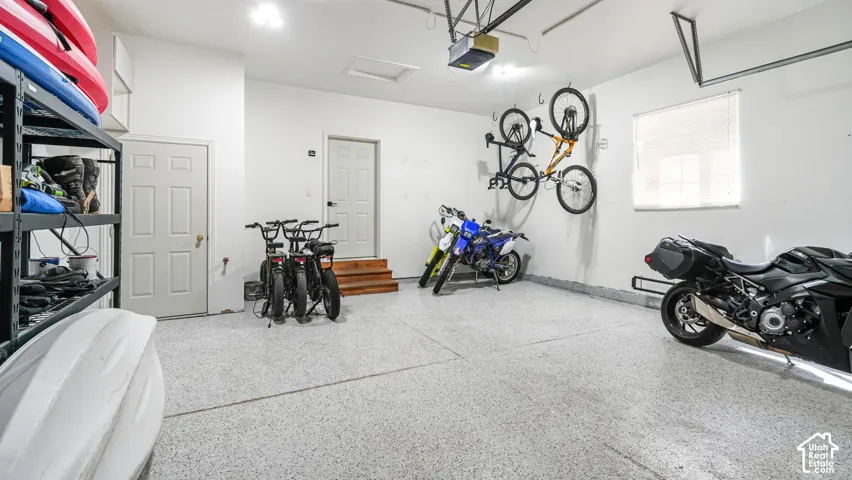 Garage featuring a speckled epoxy floor, white walls, and a window with blinds