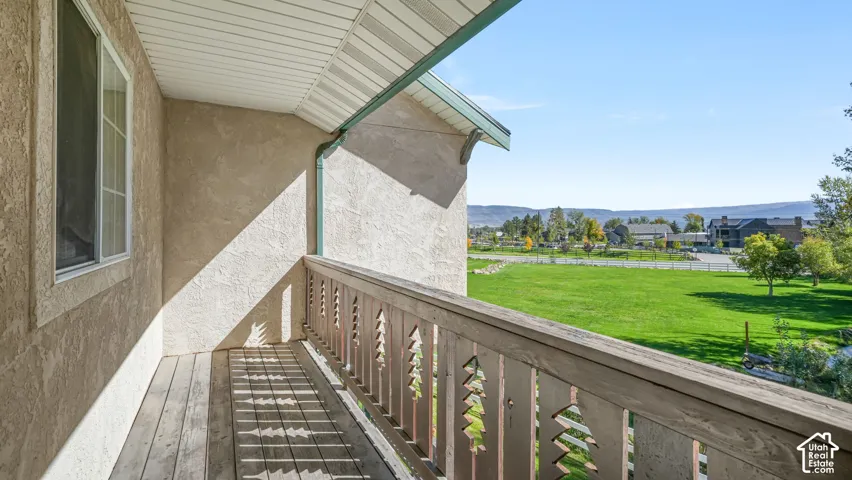 Off the master bedroom there's a covered balcony with wood-finish flooring, decorative wood railing, and stucco exterior