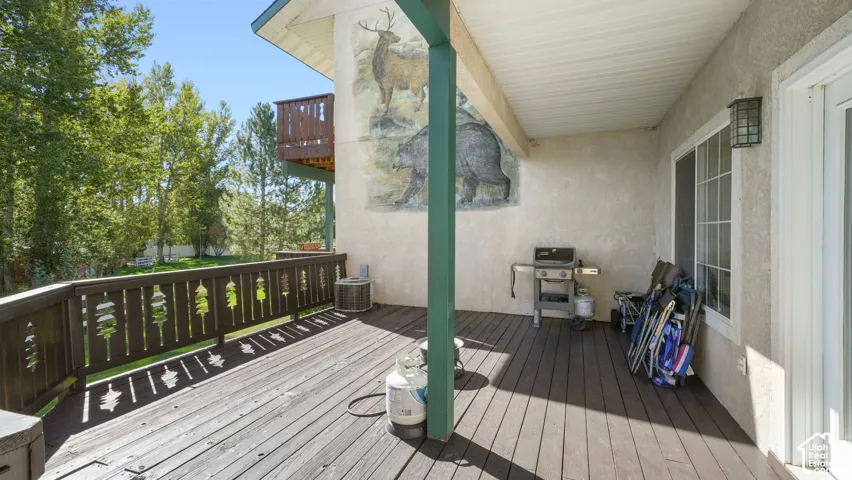 Expansive wood-finish deck with decorative wood railing and overhead coverage