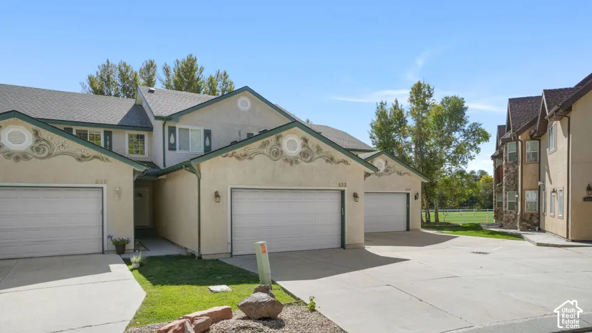 Two-story stucco building with dual garages, gabled rooflines, and decorative exterior accents