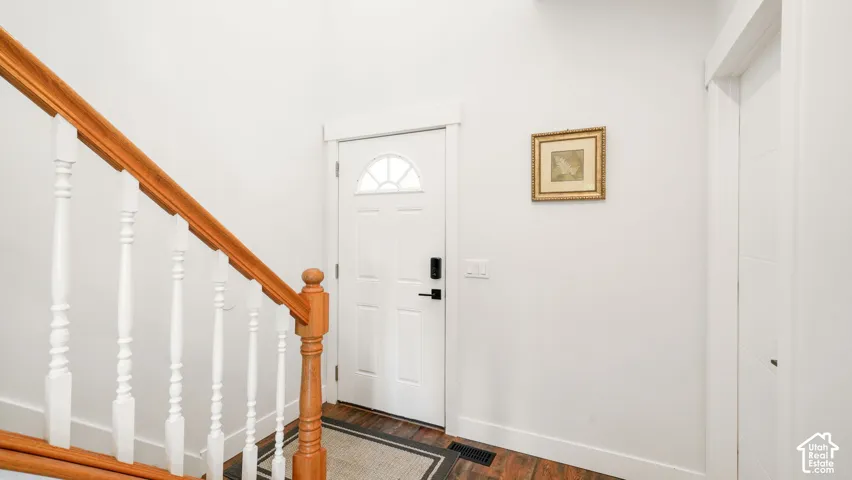 Wood-finish flooring, white paneled door with arched transom, and light wood staircase with white balusters