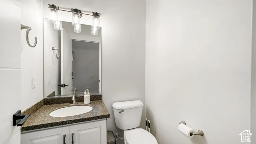White vanity with a brown speckled countertop, an undermount sink, and a brushed nickel faucet
