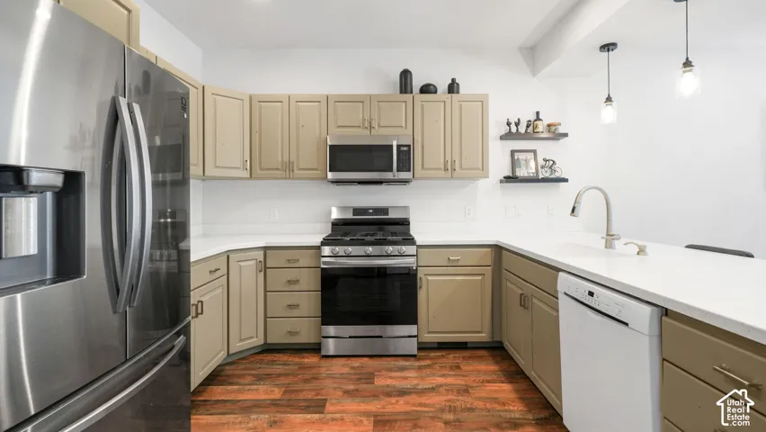 Kitchen featuring stainless steel appliances, light-toned cabinetry, white countertops, a subway tile backsplash, and wood-finish flooring