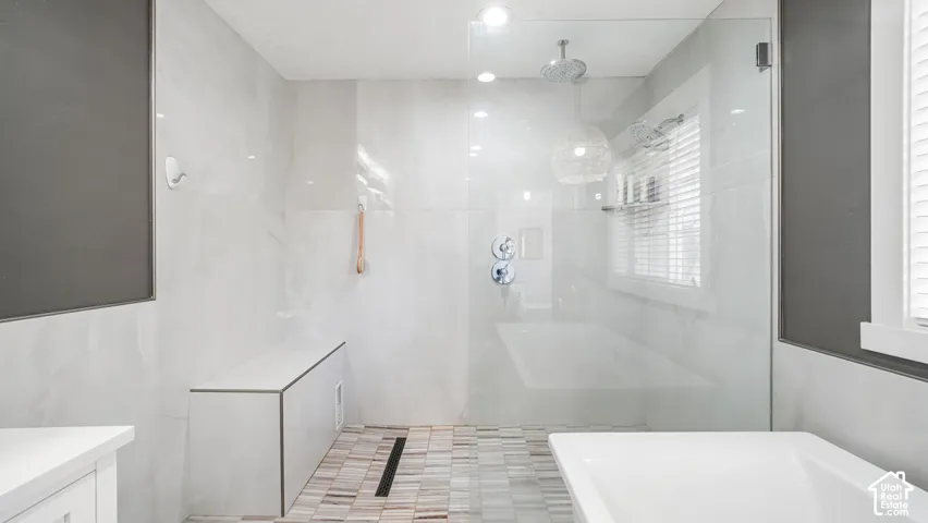 Glass-enclosed shower with a rain showerhead, built-in bench, and mosaic tile flooring