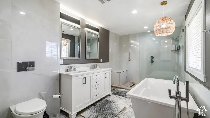 Master bath has dual vanity with white cabinetry, a freestanding soaking tub, walk-in shower with clear glass enclosure, and modern pendant light fixture
