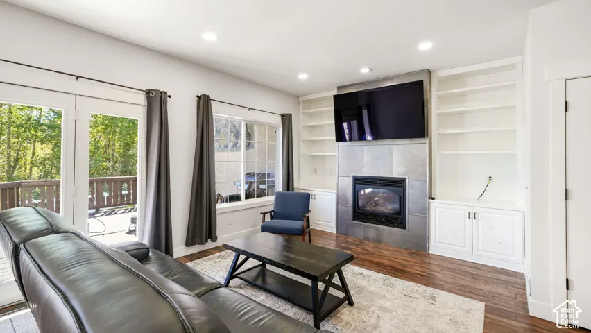 Wood-finish flooring, recessed lighting, and a fireplace with a tile surround
