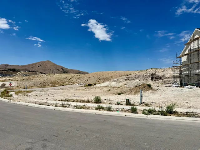 Expansive undeveloped parcel with paved road frontage, mountain backdrop, and utility access