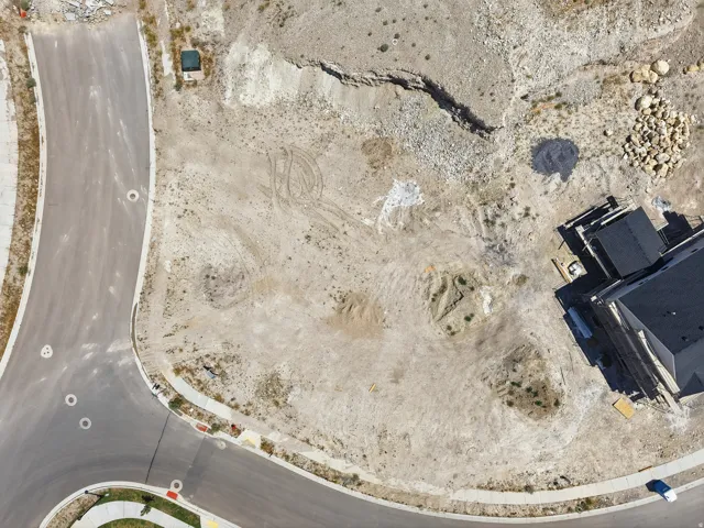 Vacant lot featuring cleared earth, visible tire tracks, and a partially constructed building on one border