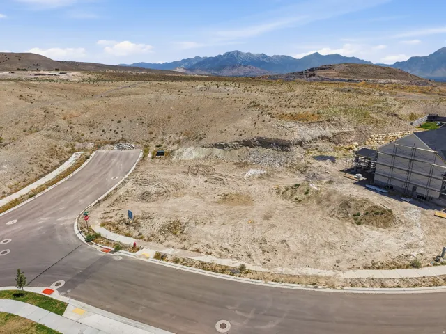 Expansive vacant lot with paved road frontage, defined curbs, and a concrete sidewalk