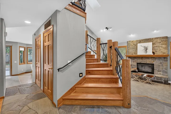 Entryway featuring flagstone flooring, wood-paneled doors, and a custom wood staircase with decorative wrought iron railing