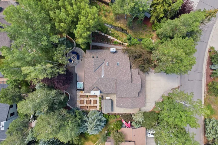 Expansive property featuring mature trees, multi-level landscaping, a circular stone patio with a built-in fire pit, a hot tub, and raised garden beds