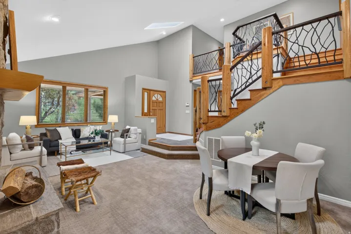 Two-story living area with a distinctive wood staircase featuring custom black ironwork railings