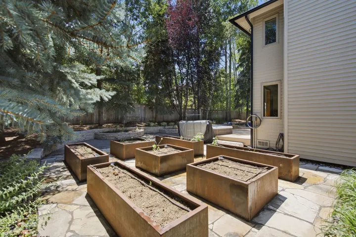 Expansive flagstone patio area featuring multiple rectangular raised garden beds