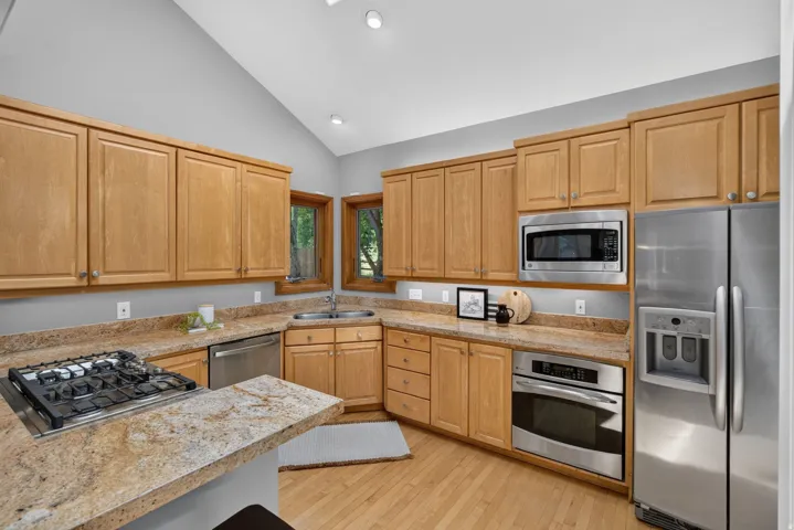 Kitchen featuring wood cabinetry, stainless steel appliances, a gas cooktop, a built-in oven, and wood-finish flooring