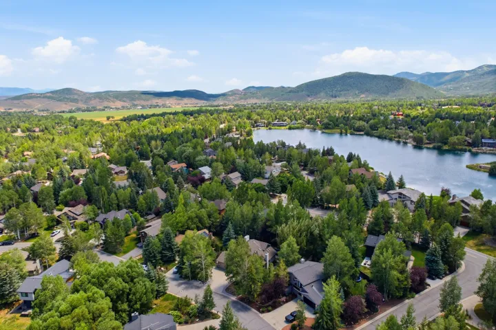 Tree-lined residential area featuring a prominent lake and surrounding mountains