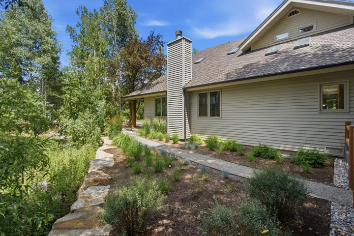 Exterior siding with multiple windows and a shingled roof, featuring a chimney with horizontal siding