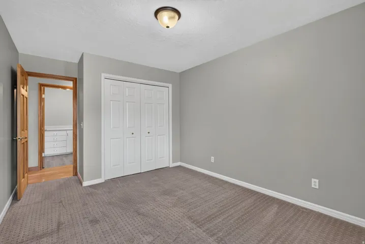 Interior room featuring textured carpet flooring, light gray wall paint, and white baseboards