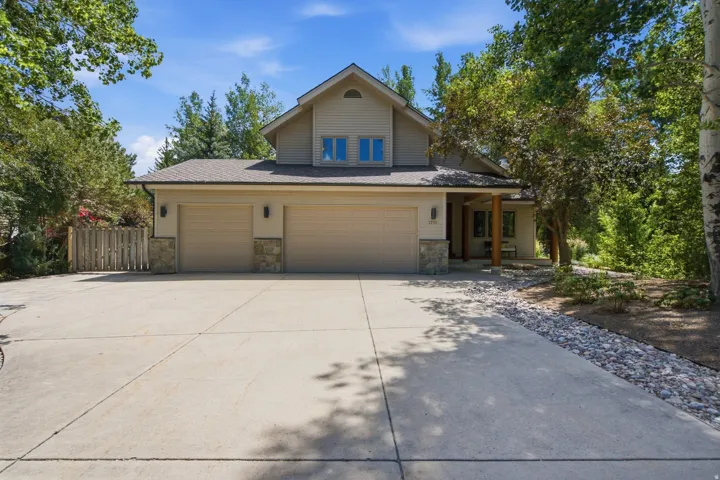 Contemporary home exterior featuring a neutral palette, a two-car garage with carriage-style doors, and stone accents