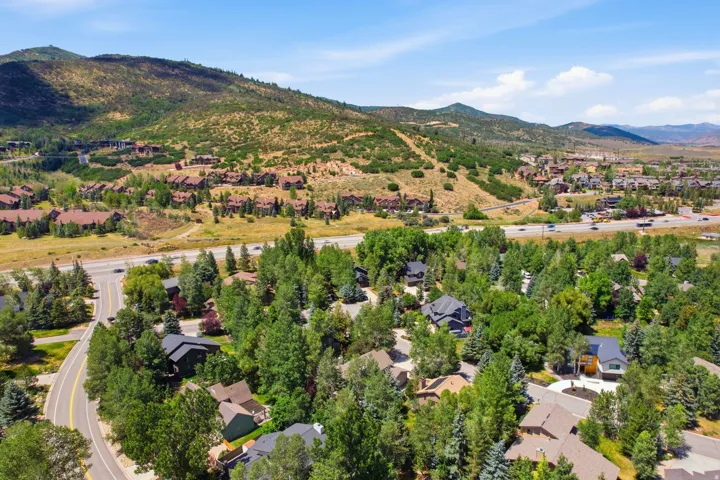 Aerial perspective showcasing a residential area with varied home styles, mature trees, and mountainous terrain