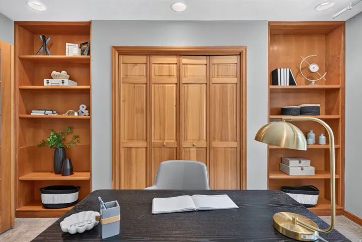 Integrated wood-finish shelving units flanking a wood-finish closet with bi-fold doors