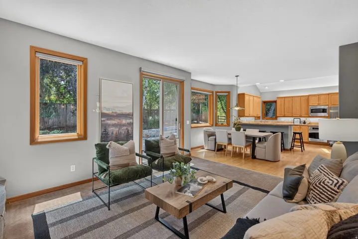 Open-concept living space featuring wood-finish flooring, a slider to the exterior, and large windows with wood trim