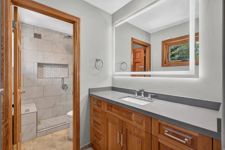 Bathroom featuring a wood-finish vanity with a light gray countertop and integrated sink