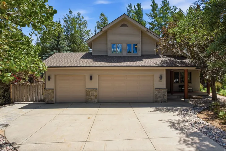 Exterior featuring a two-car garage with stone accents, a concrete driveway, and an inviting covered entry