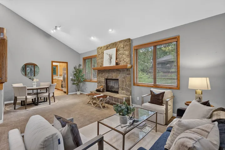Vaulted ceilings elevate this living space featuring a stone-clad fireplace with a wood mantle