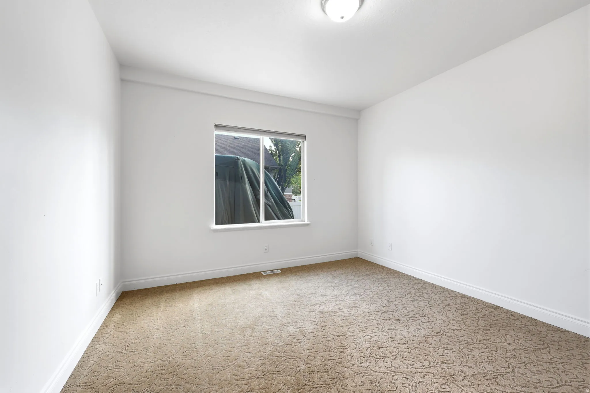 Room featuring a single window, neutral wall paint, patterned carpeting, and white baseboards