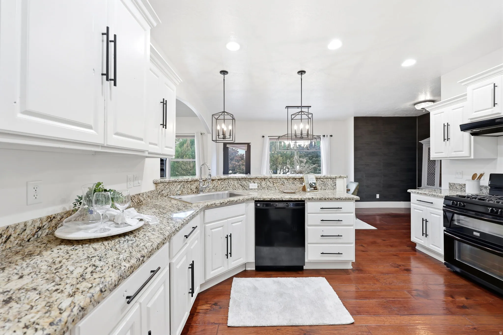 Kitchen featuring white cabinetry with black hardware, granite countertops, and wood-finish flooring