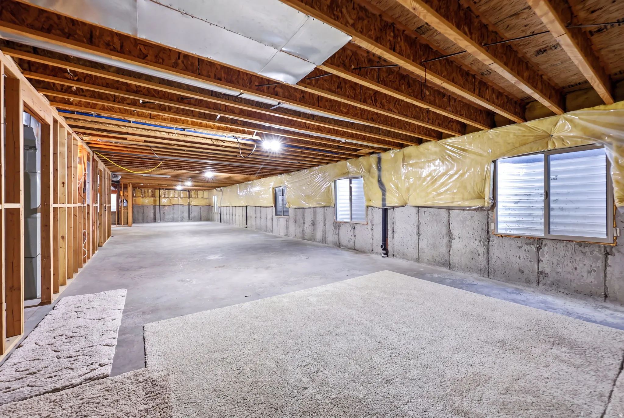 Unfinished basement featuring exposed wood joists and concrete flooring