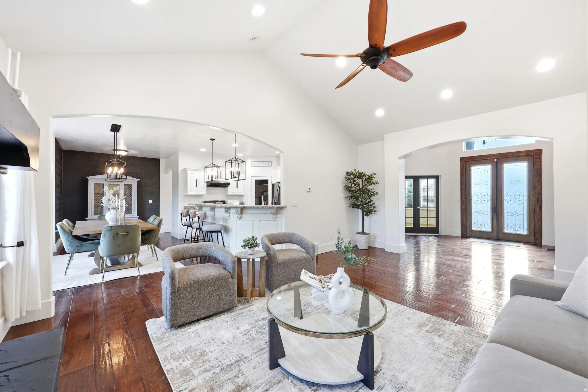 Vaulted ceiling living area with wood-finish flooring, recessed lighting, and a ceiling fan