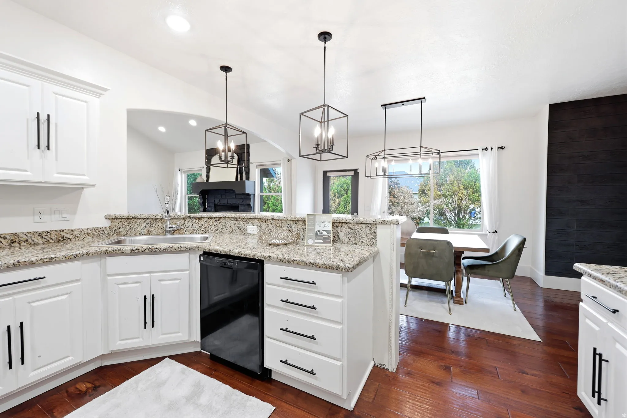 Contemporary kitchen featuring white cabinetry with black hardware, granite countertops, and a built-in black dishwasher