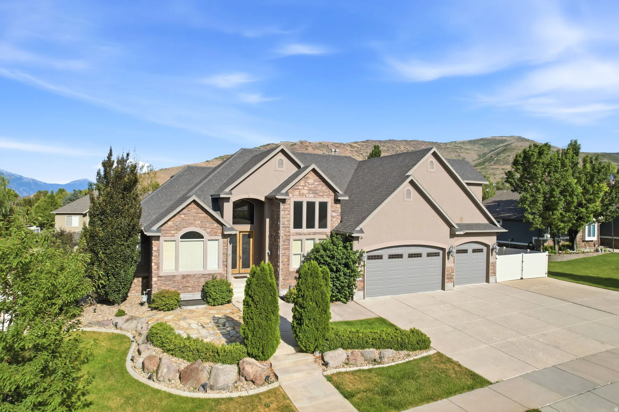 Stone and stucco exterior with multiple gables and a multi-car driveway