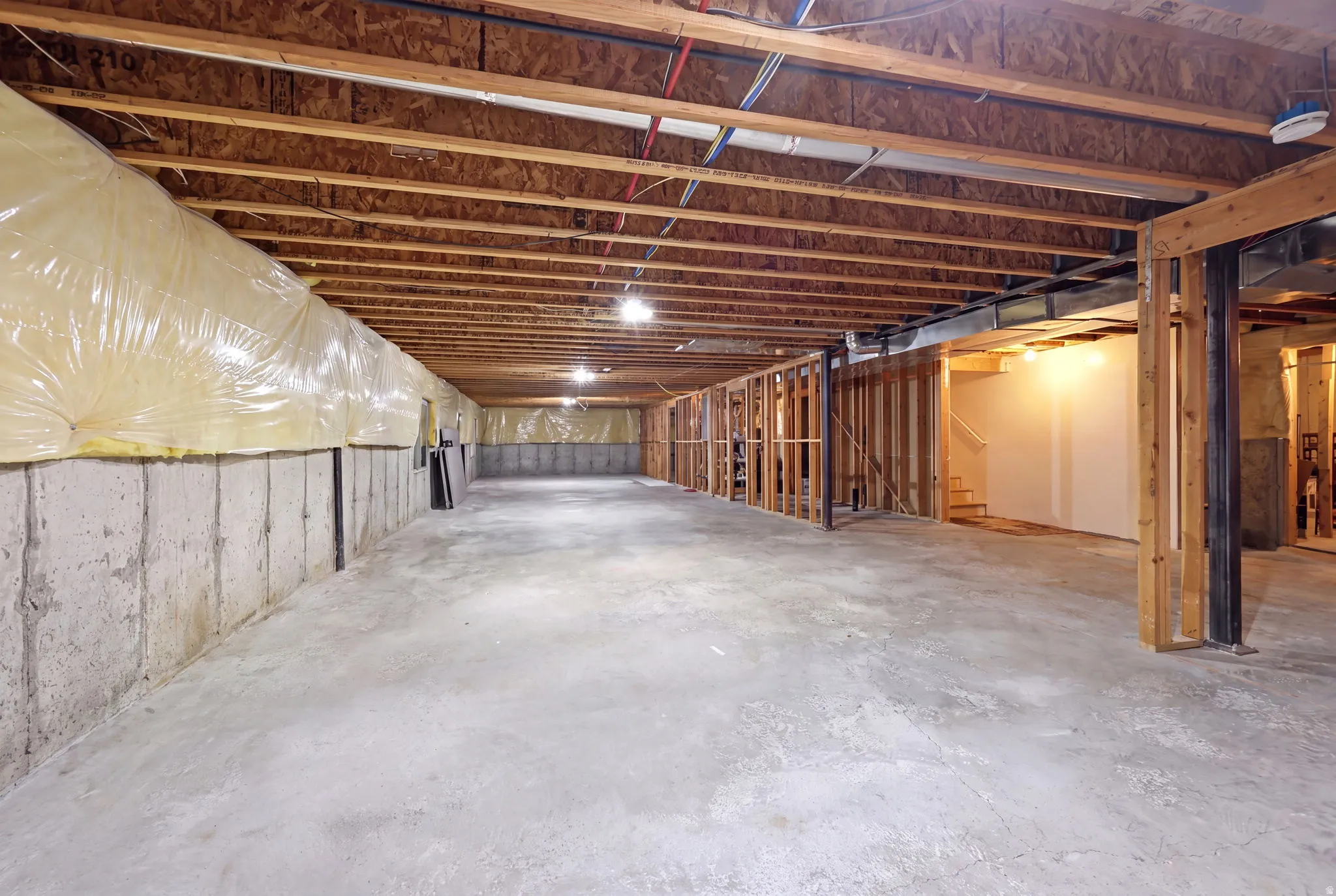 Expansive unfinished lower level featuring exposed wood joists and concrete flooring