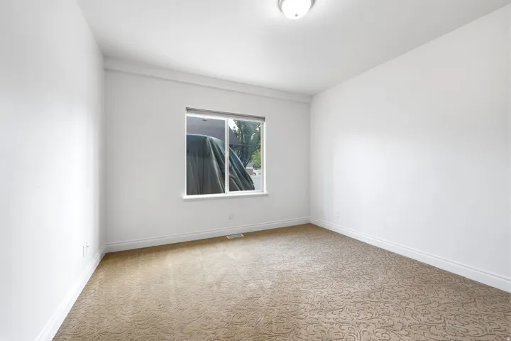 Room featuring a single window, neutral wall paint, patterned carpeting, and white baseboards