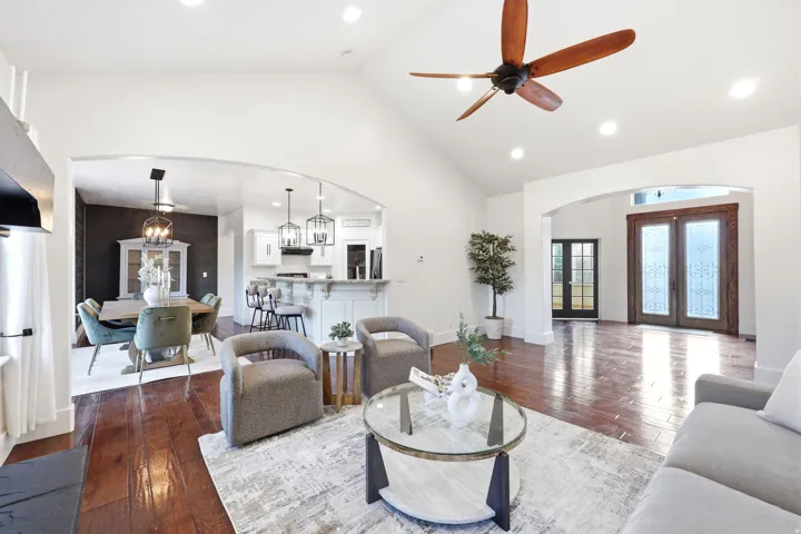 Vaulted ceiling living area with wood-finish flooring, recessed lighting, and a ceiling fan