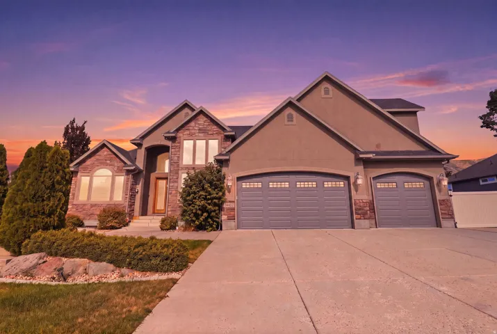 Stucco and stone facade home featuring a prominent two-car garage with carriage-style doors