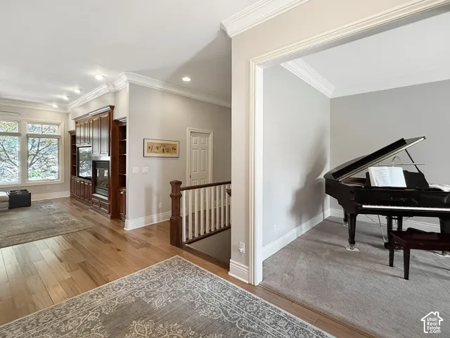 Hallway with natural light, hardwood flooring and crown molding.