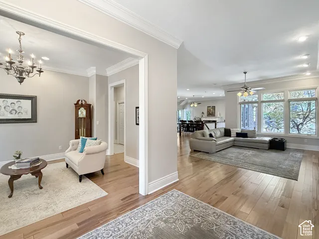 Sitting room that is an optional formal dining room. Featuring crown molding, chandelier, and hardwood flooring,